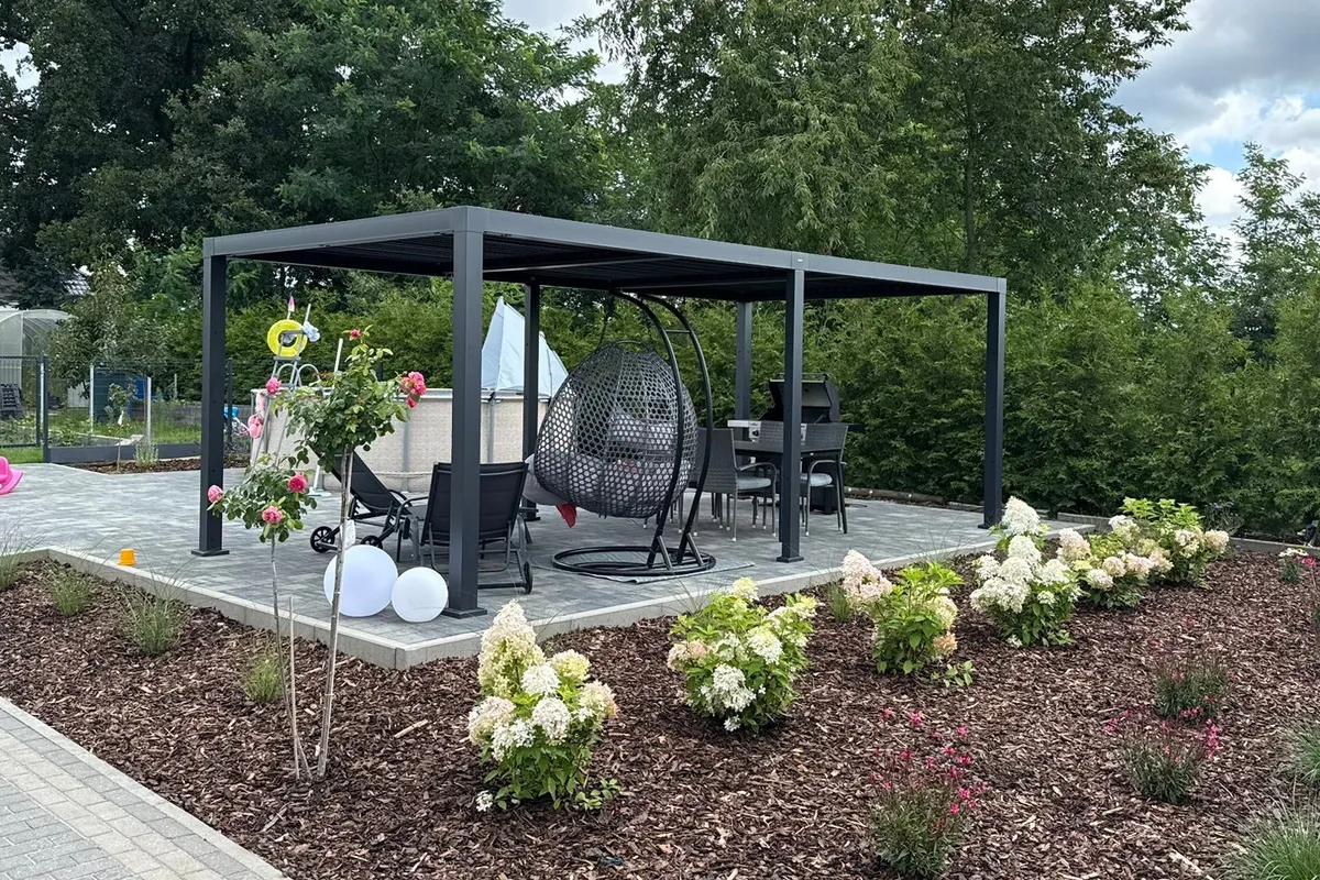 Antracytowa pergola z huśtawką i nasadzeniami w ogrodzie przydomowym